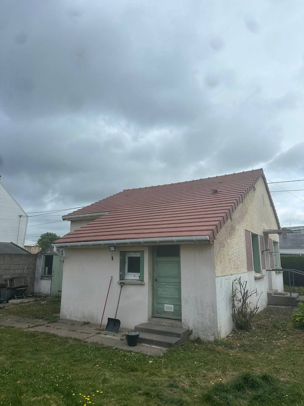 Petite maison crépie à toiture en tuiles rouges