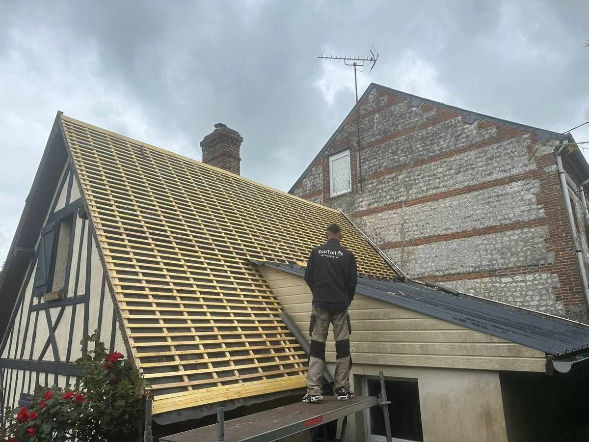 Couvreur Eco Toit debout sur les liteaux neufs d'une toiture en cours de réfection, maison à colombages