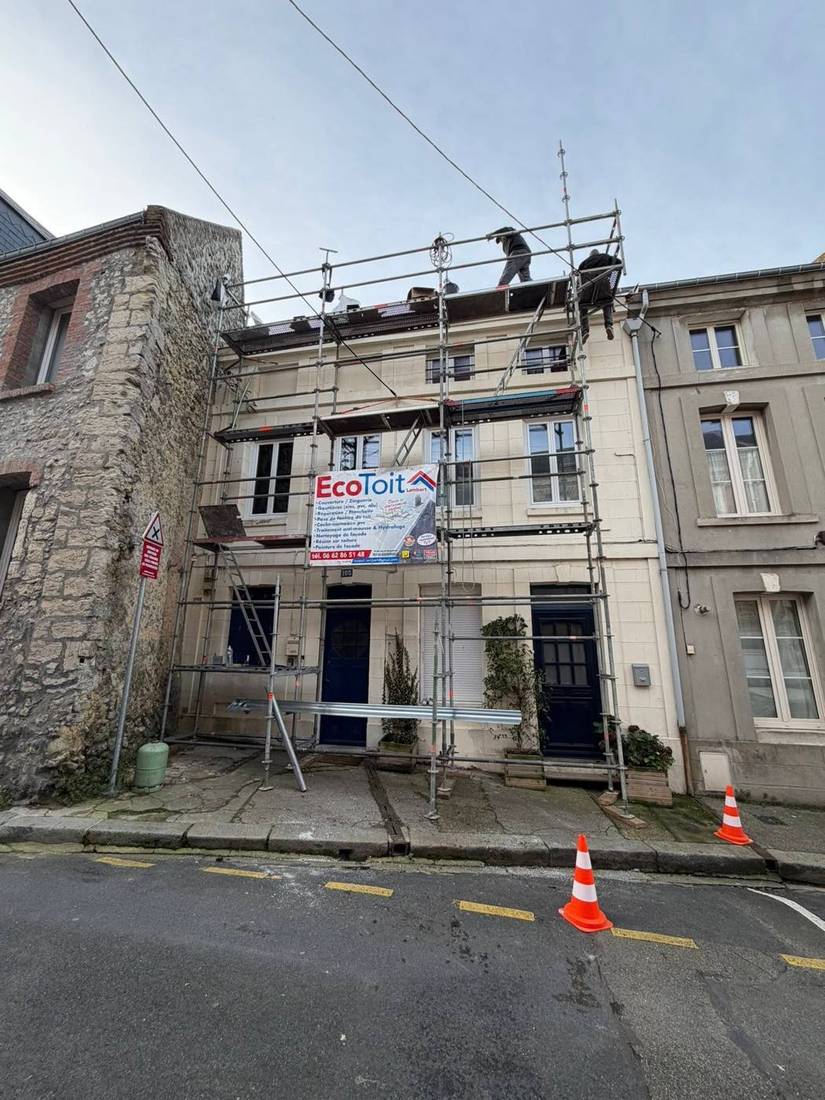 Échafaudage sur une maison de ville en pierre, couvreurs au travail sur le toit