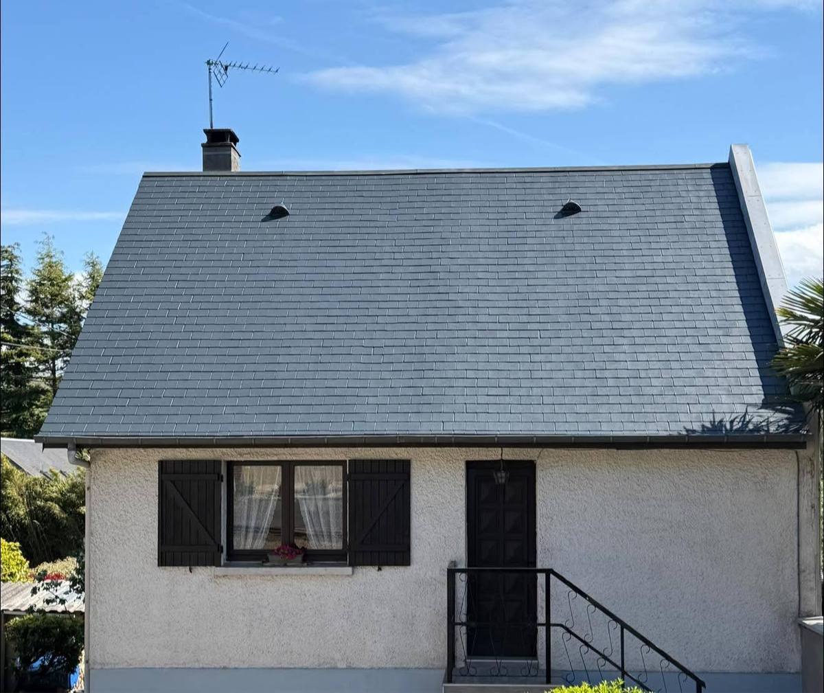 La même maison blanche avec sa toiture en ardoise propre après démoussage
