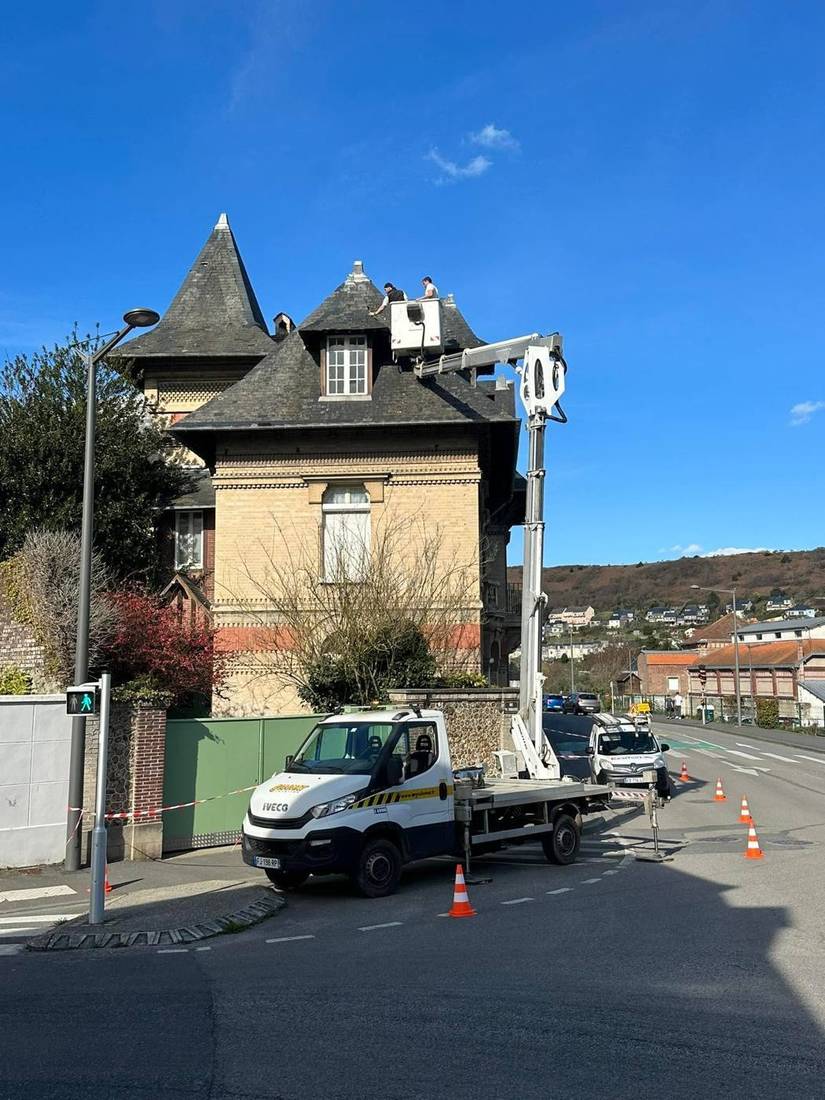 Nacelle déployée devant une grande maison en brique à toiture en ardoise et tourelle