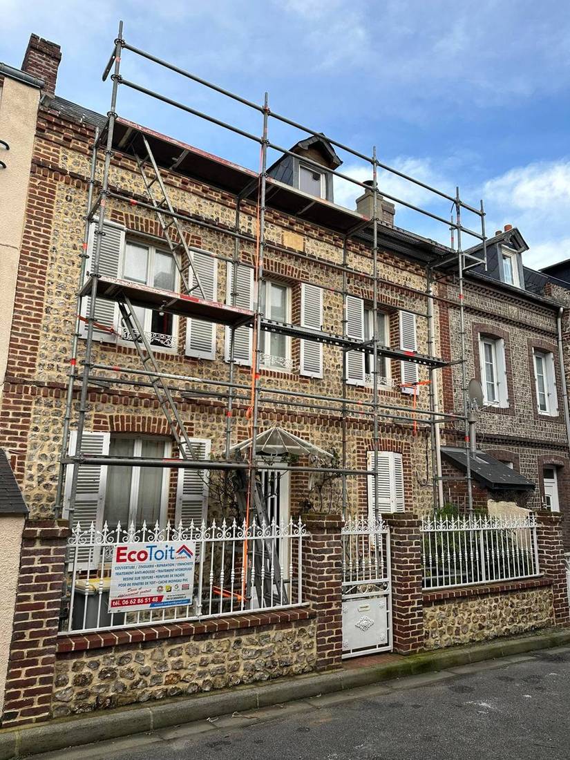 Maison de ville en brique et silex sous échafaudage, panneau Eco Toit sur la clôture
