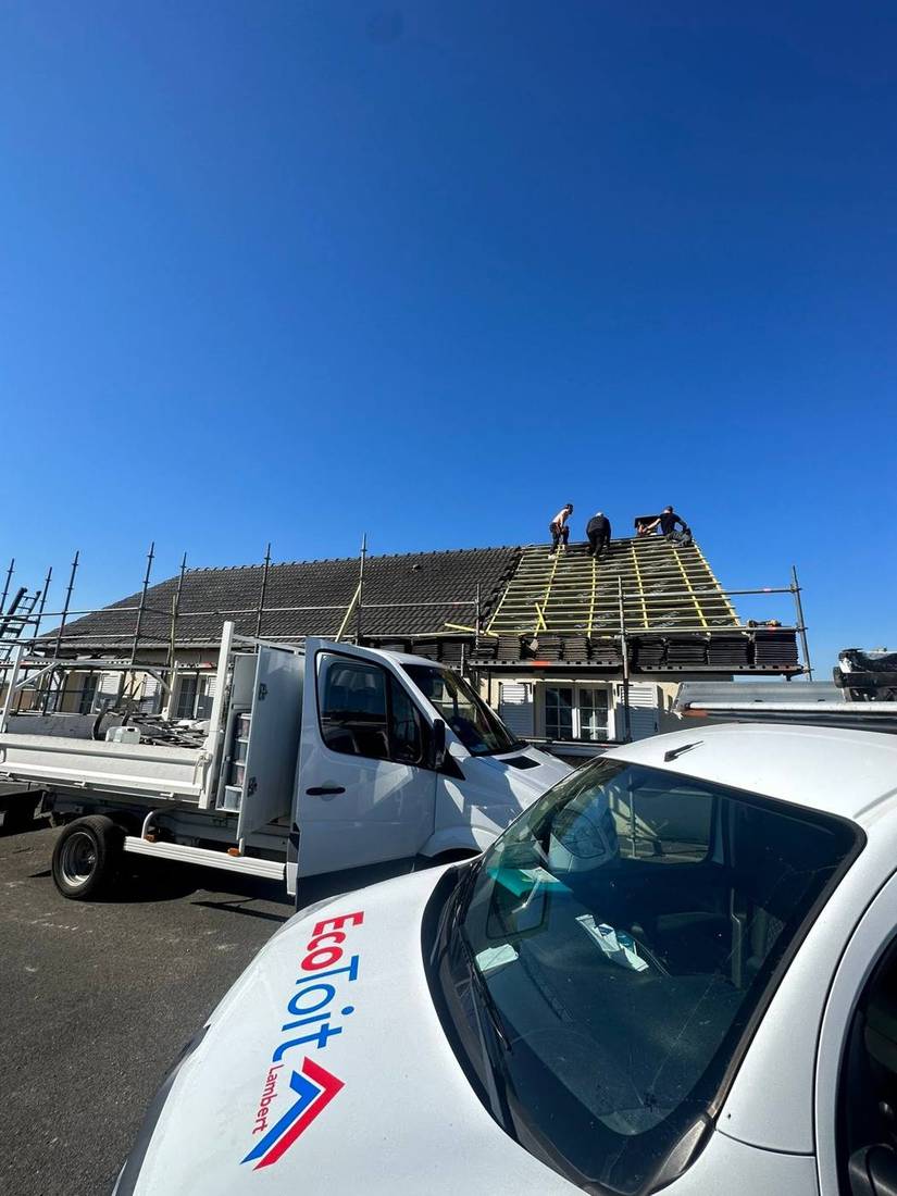 Camion plateau et fourgon Eco Toit garés devant une maison dont la couverture est en cours de réfection