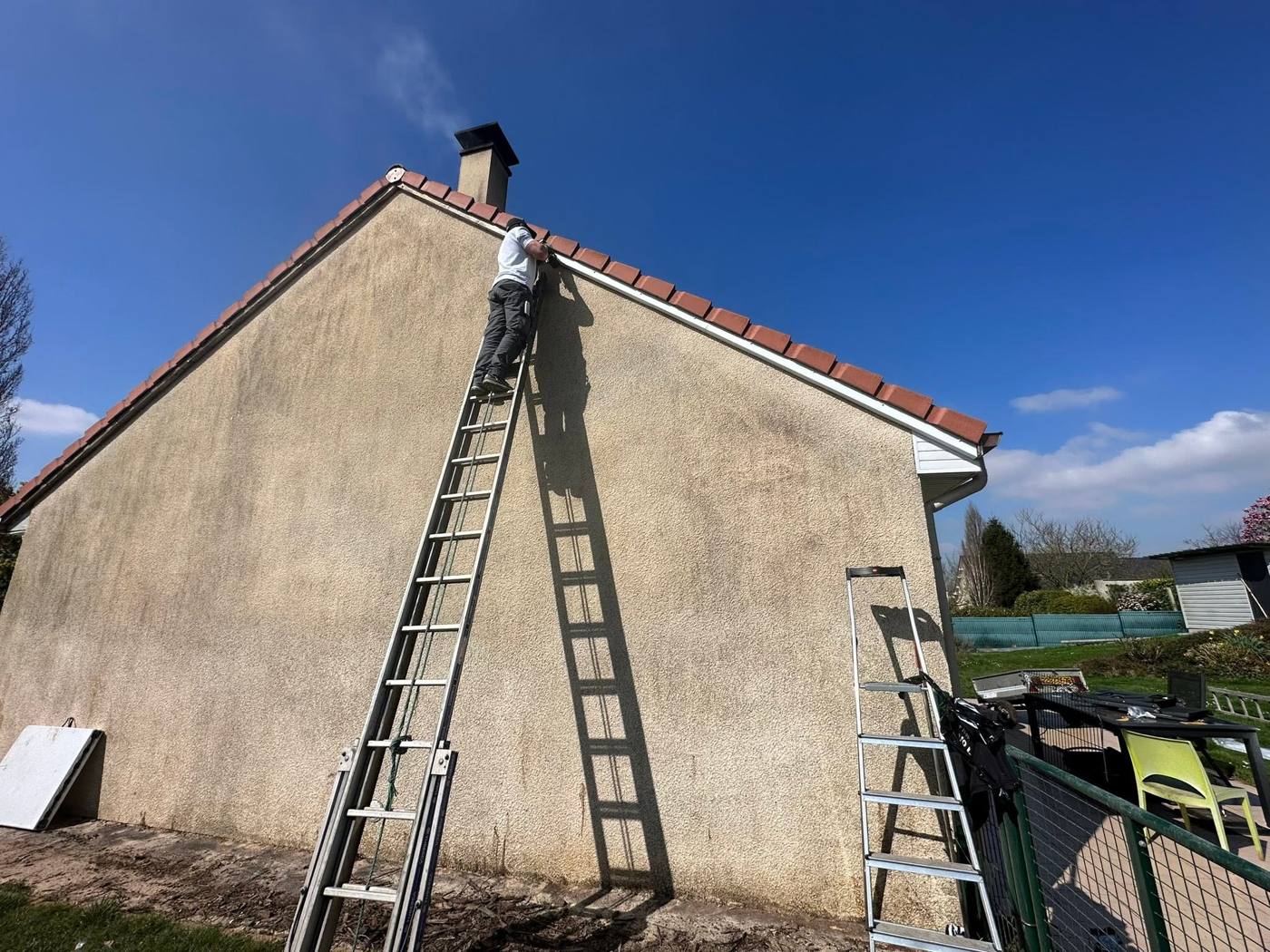 Pignon enduit d'une maison avec une échelle posée contre le mur