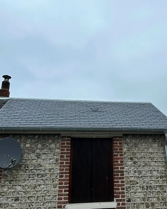 Toiture en ardoise propre sur une maison en silex et brique